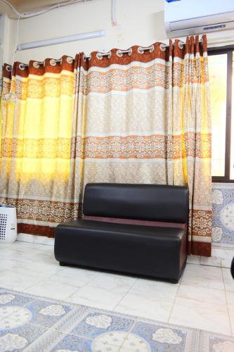 a black couch in front of a curtain at Kompass - Home Stay in Dhaka