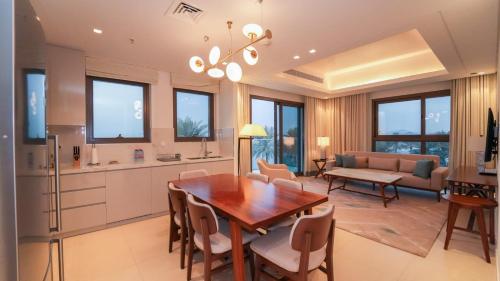 a kitchen and living room with a wooden table and chairs at Solo Realty Apartments at Address Residence Fujairah in Sharm