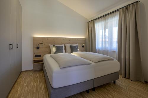 a bedroom with a large white bed and a window at Alpensonne Apartments in Bad Wiessee
