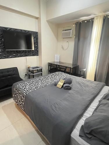 a bedroom with a large bed and a tv at Aurora Escalades Residences in Manila