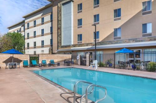 a pool in front of a building with chairs and umbrellas at Hampton Inn & Suites Riverside/Corona East in Riverside