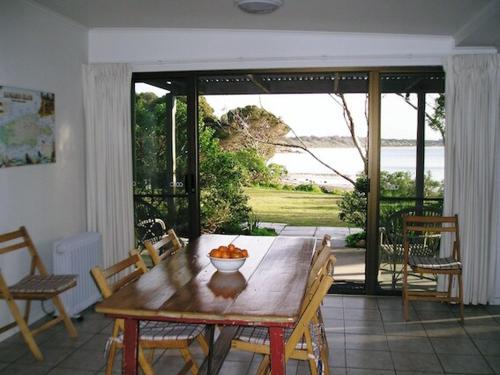 a dining room with a wooden table and a view of the ocean at The Beach House, Kangaroo Island in Baudin Beach