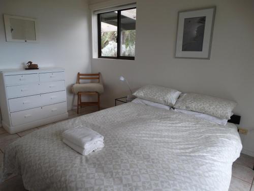 a bedroom with a bed and a dresser and a window at The Beach House, Kangaroo Island in Baudin Beach
