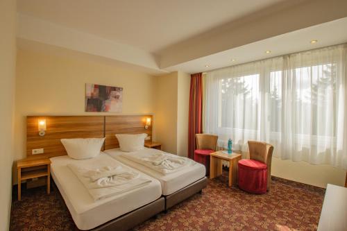 a bedroom with a bed and a desk and a window at Ferien Hotel Rennsteigblick in Friedrichroda