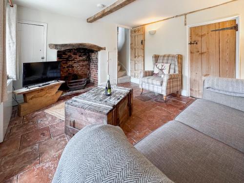 a living room with a couch and a fireplace at Rosemary Cottage in Mattishall