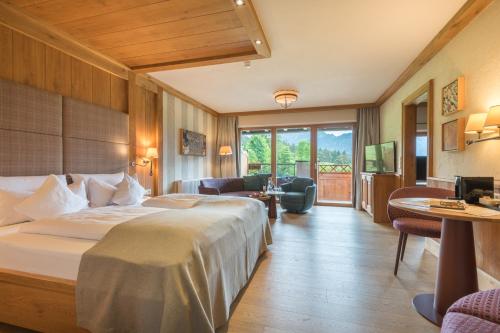a hotel room with a bed and a living room at Hotel Bergblick 5 Sterne in Grän