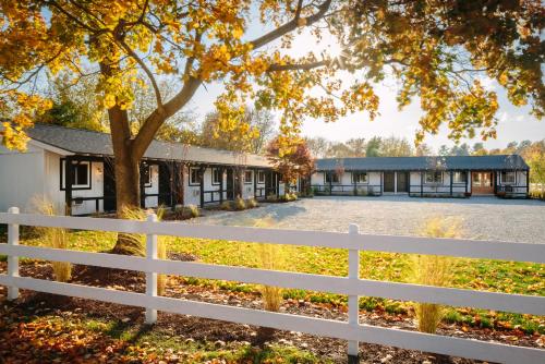 a white fence in front of a building with a tree at Brentwood Hotel in Saratoga Springs