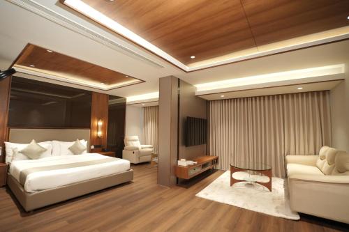 a bedroom with a bed and a couch and a table at Hotel Bluebell in Kozhikode