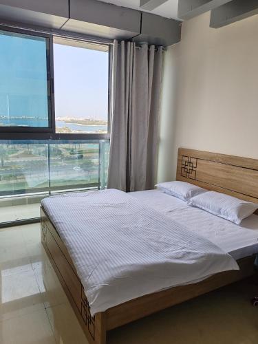 a bed in a bedroom with a large window at King bed sea view in Sharjah