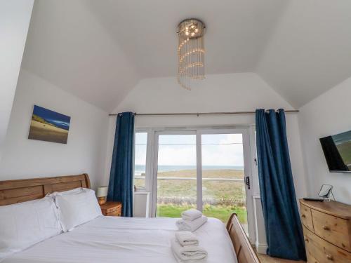 a bedroom with a bed and a large window at Farne Cottage in Beadnell