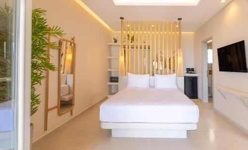 a bedroom with a white bed with a gold headboard at EvMariA suites in Fira