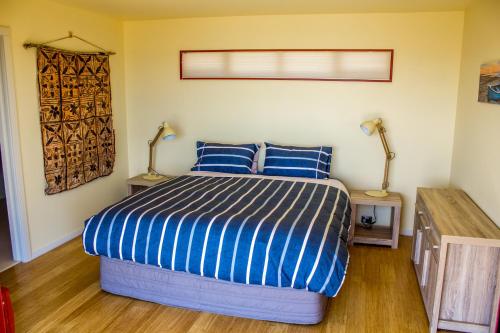 a bedroom with a bed with blue and white sheets at Sunrise Apartment - Golden Bay in Onekaka