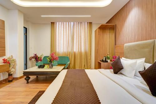 a hotel room with a bed and a table and chairs at Olive Aero Suites Plaza Inns Near Delhi International Airport in New Delhi