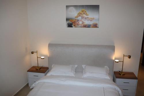 a bedroom with a large white bed with two night stands at imperial homes 2 in Ajman 