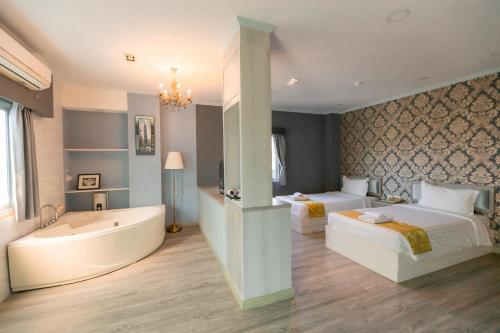 a bathroom with two beds and a bathtub and a bedroom at Napheera Royal Tel in Ban Khlong Bang Krathiam