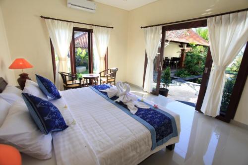 a bedroom with a large bed with blue and white sheets at Uma Budhas in Ubud