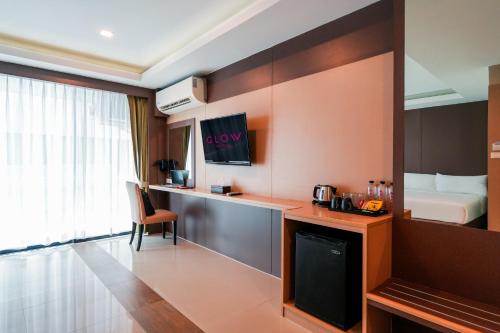 a hotel room with a desk and a bed at GLOW Pattaya in Pattaya South