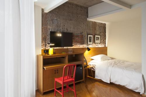 a bedroom with a bed and a desk with a television at Zhuhai Bei Shan Ju Art Hotel in Zhuhai