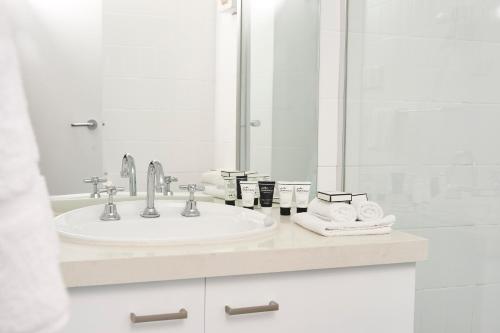 a white bathroom with a sink and a mirror at Abom Hotel in Mount Buller