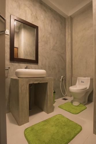 a bathroom with a sink and a toilet and green rugs at Explore Sinharaja Rain Forest Tour Camp in Dombagoda