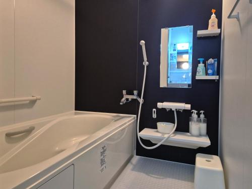 a bathroom with a tub and a sink and a mirror at KitaのHikari in Sapporo
