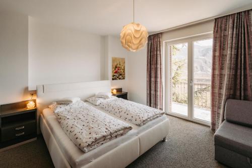 a bedroom with a bed and a large window at Zeder Kraiterhof in Andrian