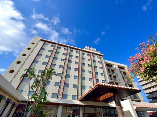 a tall white building with a blue sky in the background at Community & Spa Naha Central Hotel in Naha