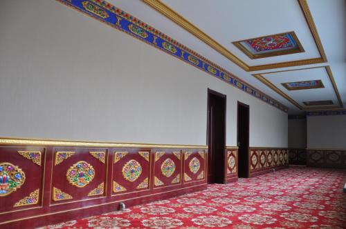 an empty room with a ceiling and a red carpet at Overseas Tibetan Hotel in Xiahe