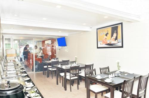 a dining room with tables and chairs and people in the kitchen at Hotel Bond in Yangon