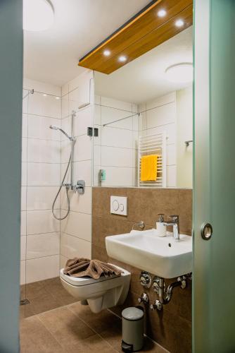 ein Badezimmer mit Waschbecken, Toilette und Dusche in der Unterkunft Boutique-Hotel Con4rent in Kirchheim unter Teck