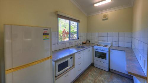 a kitchen with a stove top oven and a microwave at Batchelor Holiday Park in Batchelor