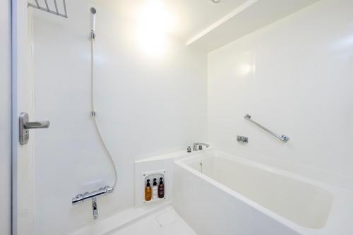 a white bathroom with a shower and a sink at Smile Hotel Kyoto Shijo in Kyoto