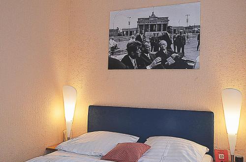 a black and white picture above a bed with two lights at Retro - Art - Hotel Lünen in Lünen