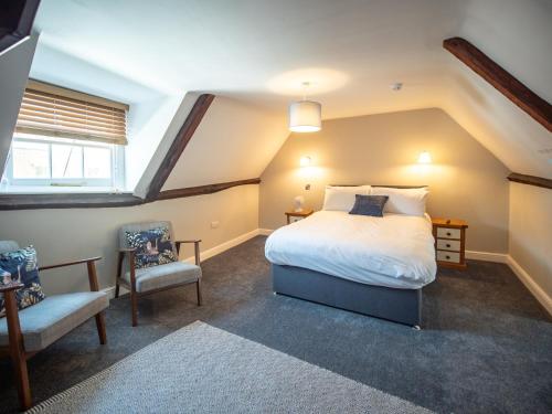 a attic bedroom with a bed and a chair at The Crown in Poole