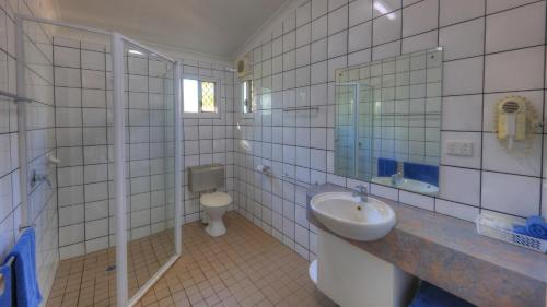 a bathroom with a toilet, sink, and shower at Batchelor Holiday Park in Batchelor
