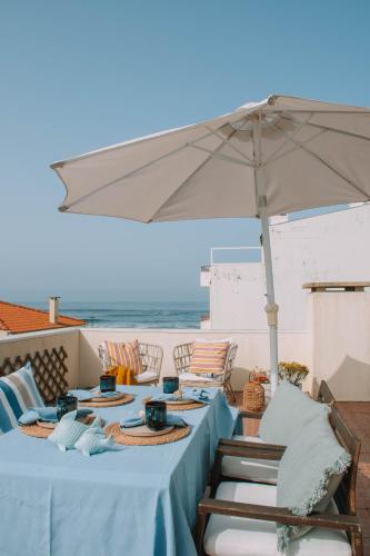 a table with a blue table cloth and an umbrella at Casas dos Seixos in Moledo