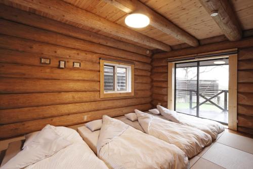 a bed in a room with wooden walls at ヴィラ湖西 最大11名 琵琶湖ビュー165平米の一棟貸切ログハウス BBQハウス完備 広々3LDK ロフト Wi-Fi in Takashima