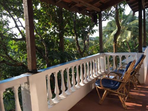 two chairs on a porch with trees in the background at Oceanic - Luxury Boutique Hotel in Palolem