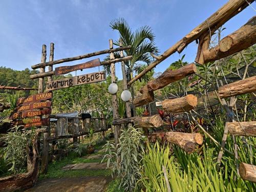 a wooden fence with a sign in a garden at Grand Whiz Hotel Trawas Mojokerto in Trawas