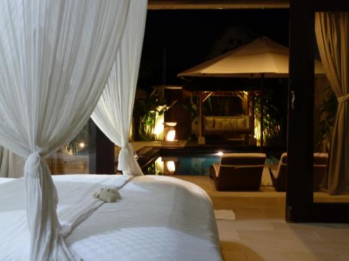 a bedroom with a bed with white curtains at La Dolce Villa in Seminyak