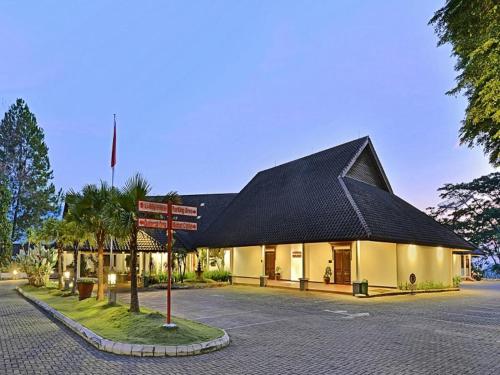 a building with a black roof and a street sign at Grand Whiz Hotel Trawas Mojokerto in Trawas