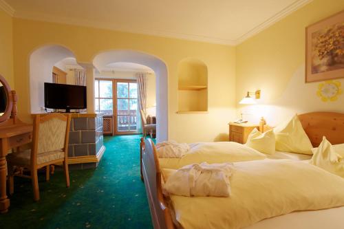 a hotel room with two beds and a television at Wellnesshotel Mitterwirt in Dienten am Hochkönig