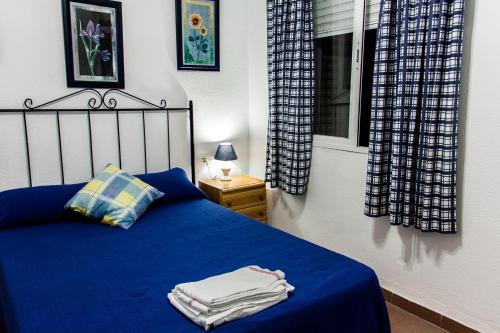 a bedroom with a blue bed and a window at Apartamento La carraca in Chipiona