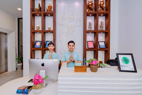 two people standing behind a desk with a computer at Homewood Hotel Siem Reap in Siem Reap