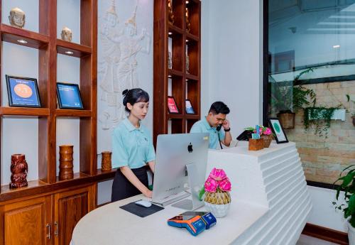 a man and a woman standing at a counter with a computer at Homewood Hotel Siem Reap in Siem Reap