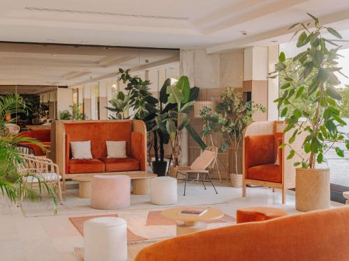 a lobby with orange chairs and tables and plants at Novotel Paris Centre Tour Eiffel in Paris