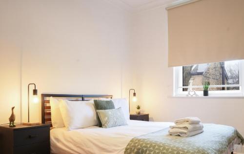 a bedroom with a bed with white sheets and a window at Modern 2 Bed Apt with Roof Terrace - Ecclesall Rd - Now Hosted by StayHostSave in Sheffield