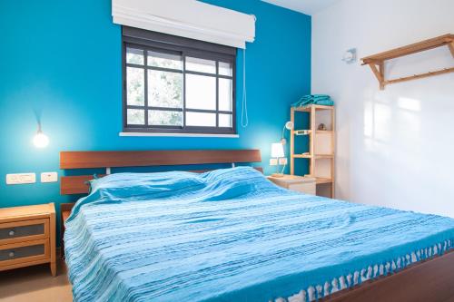 a blue bedroom with a bed and a window at Carmel Home Mount Seaview in Haifa