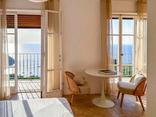 a bedroom with a table and chairs and a view of the ocean at Villa Velta Calagrande in Porto Santo Stefano