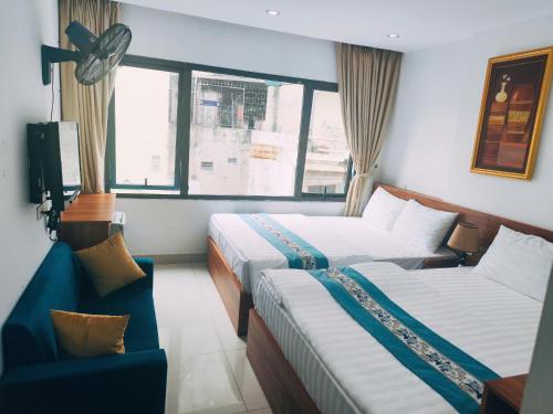 a hotel room with two beds and a chair at okaeri hotel in Hanoi